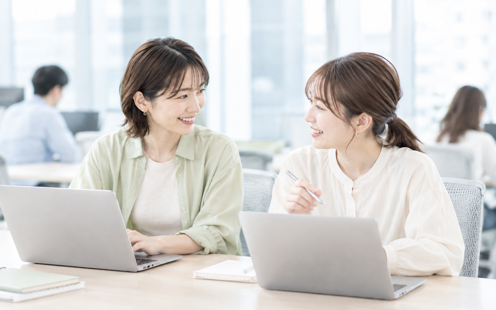 2人が話しながら仕事する写真